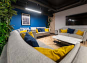 Thumbnail 8 of 8 - A living room with a grey couch and yellow pillows.
