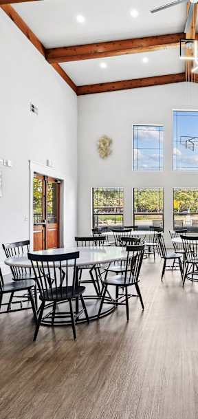 A large room with wooden floors and tables and chairs.