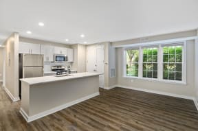 a kitchen with white cabinets and a large window