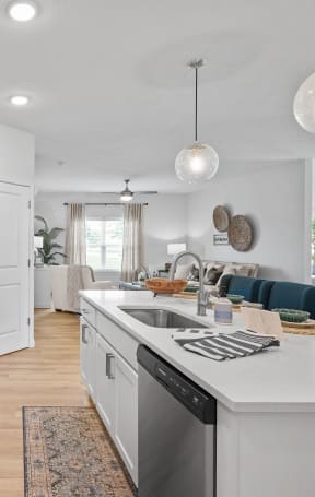 an open kitchen and living room with white cabinets and stainless steel appliances