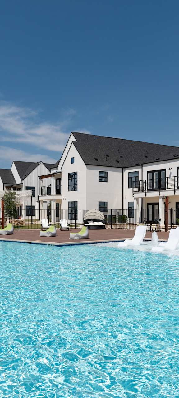 A large swimming pool in front of a row of houses.