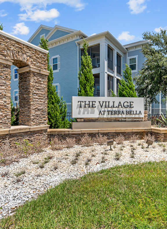a large gray apartment building with a sidewalk in front of it at Village at Terra Bella Apartments, Land O' Lakes, Florida
