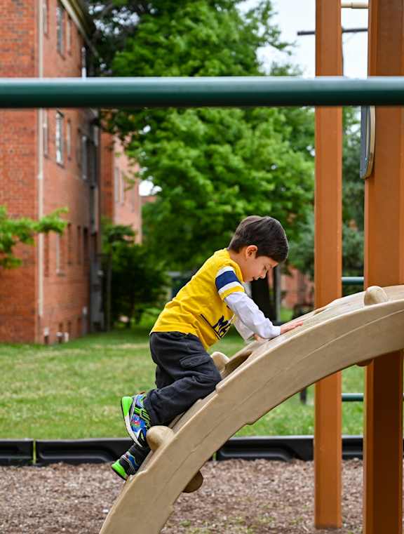 a young boy sliding down a slide on a playground at Hamilton Manor Apartments, Hyattsville, 20782