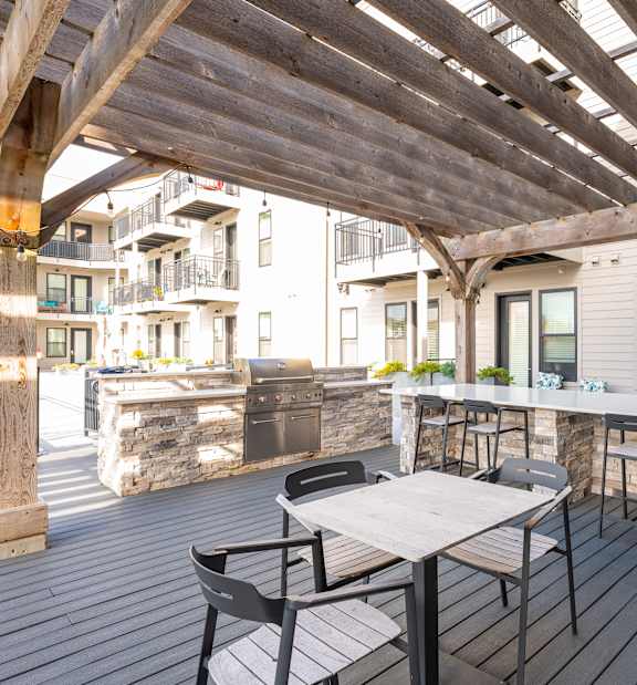 A wooden deck with a table and chairs under a wooden roof.