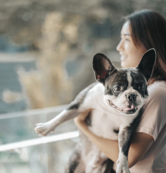 woman holding her french bulldog on her apartment balcony at Topaz Apartments, California