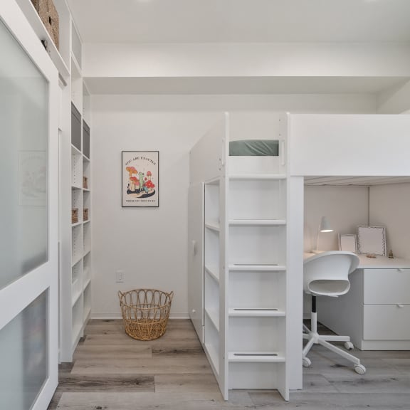 a small room with a bunk bed and a desk with a chair