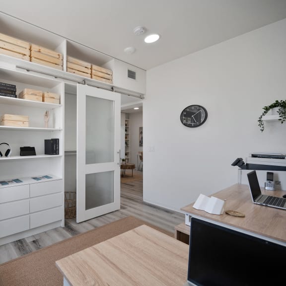 a home office with a desk and a closet with shelves