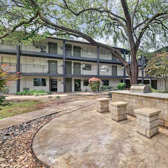 A courtyard with a brick structure in the middle and apartment buildings in the background.