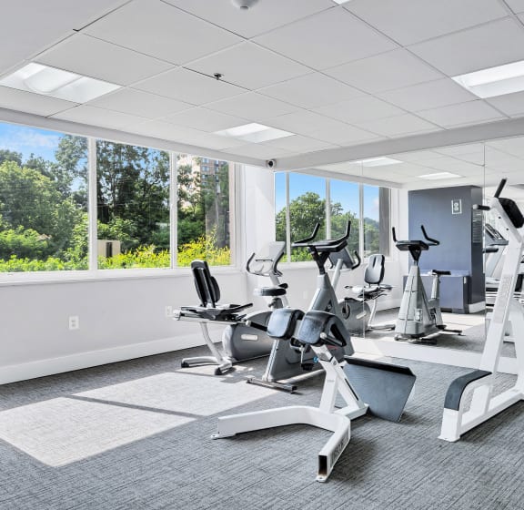 a gym with various cardio machines and windows in a building