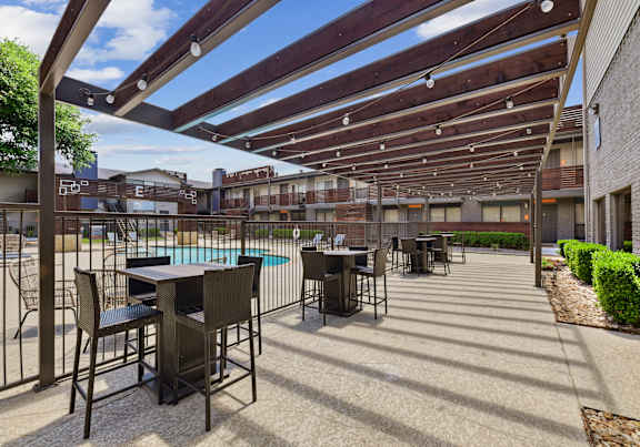 A patio with a table and chairs under a wooden pergola.