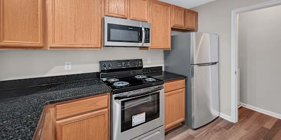 A kitchen with wooden cabinets and a black countertop.
