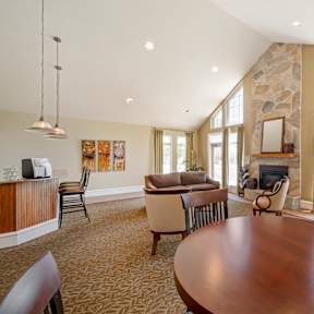 A living room with a stone fireplace and a large wooden table.