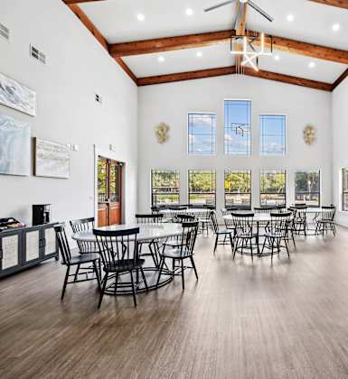 A large room with wooden floors and tables and chairs.