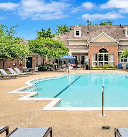a swimming pool with chairs around it in front of a house