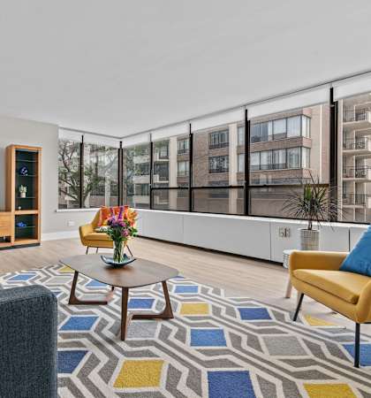a living room with white walls and a large window with a city view
