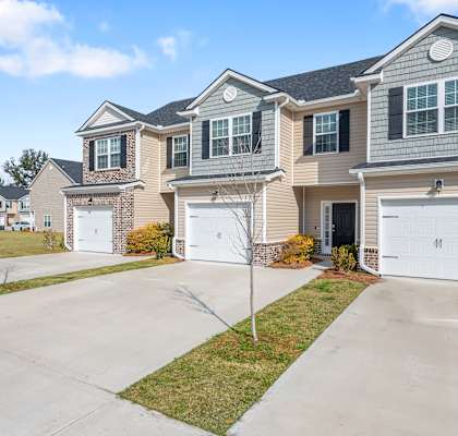 a beige house with white doors on a driveway
