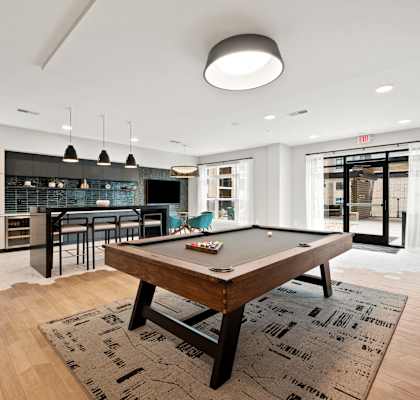 a living room with a pool table and a kitchen with a bar