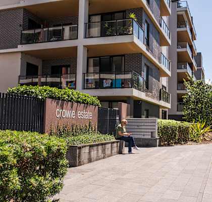 A woman is sitting on a bench in front of Crowie Estate.
