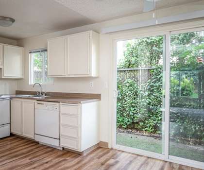an empty kitchen with white appliances and a sliding glass door