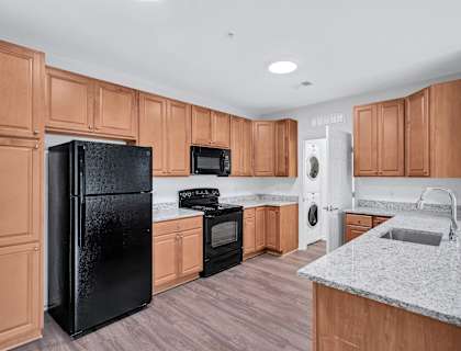 a kitchen with wooden cabinets and a black refrigerator