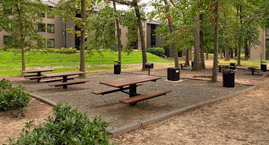 A playground with a green swing set and a brown sandy ground.