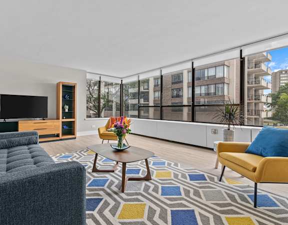 a living room with white walls and a large window with a city view