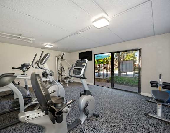 a gym with exercise machines and a sliding glass door