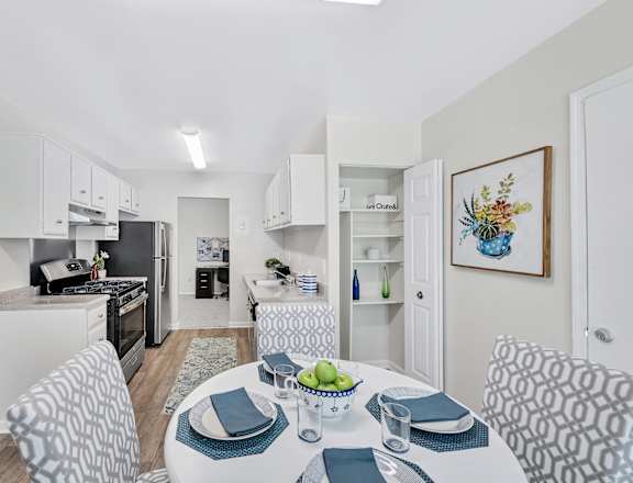 a dining area with a table and chairs and a kitchen in the background