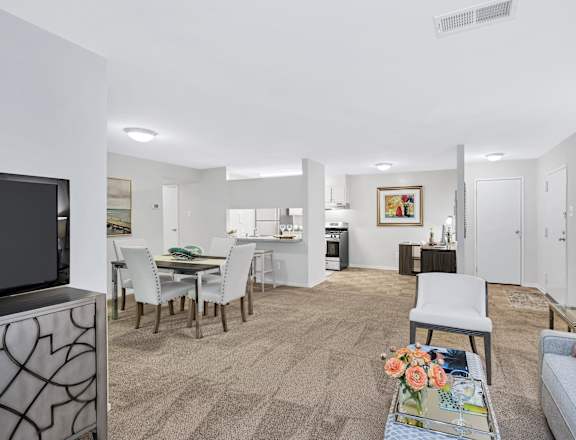 a living room and dining area with a television and kitchen in the background