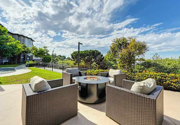 A patio with a table and chairs overlooking a green lawn.