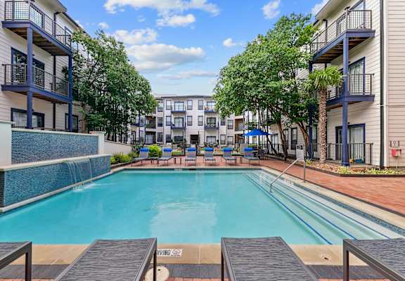 A swimming pool surrounded by apartment buildings and trees.