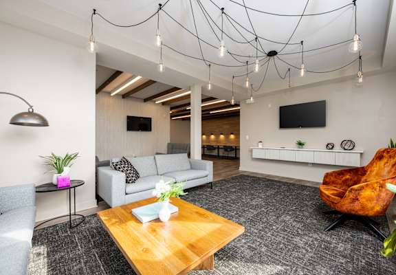 A modern living room with a wooden coffee table and a grey armchair.