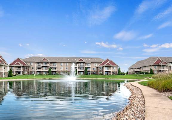 A serene lake in front of a row of apartment buildings.