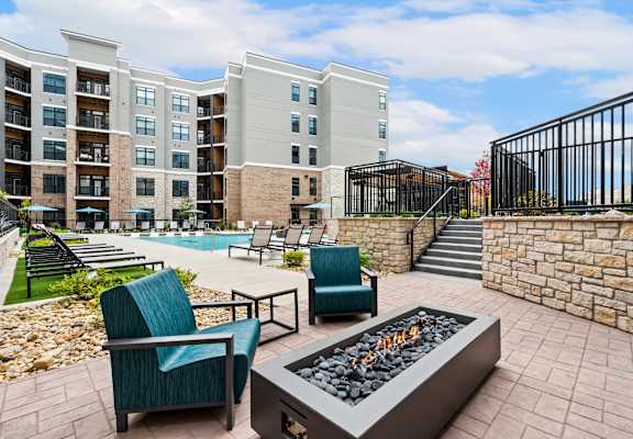 an outdoor patio with chairs and a fire pit and an apartment building
