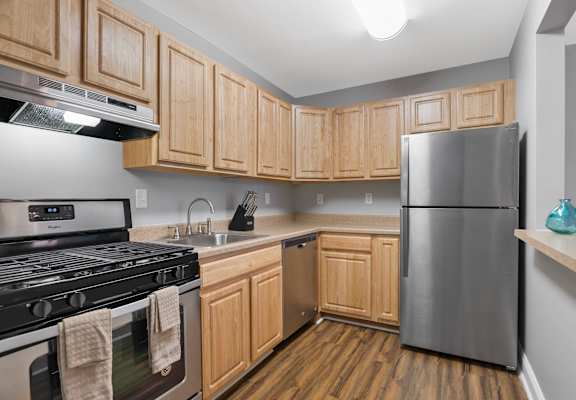 A kitchen with wooden cabinets and a stainless steel refrigerator.