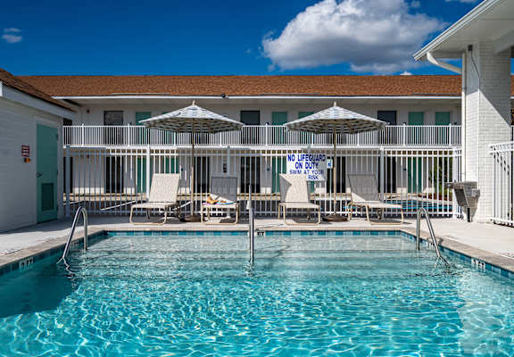 a resort style pool with chairs and umbrellas in front of a building at The Teale Navy Yard, North Charleston, SC, 29405