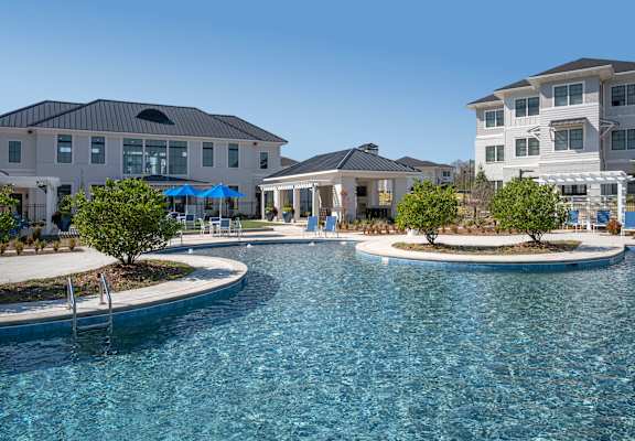 A large swimming pool in front of a row of houses.