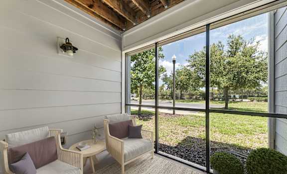 A patio with a couch, chairs, and a table with a potted plant on it.
