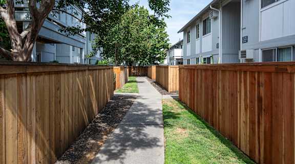 a sidewalk in front of a wooden fence