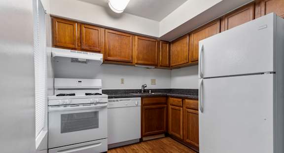 A kitchen with white appliances and wooden cabinets.