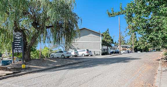 A street view with a signboard and cars parked on the side.