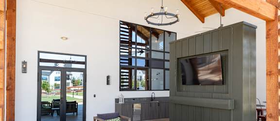 A modern outdoor seating area with a television and comfortable cushions.