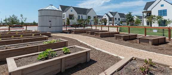 A garden with raised beds and a water tank in the background.