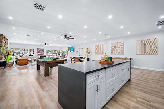 A modern kitchen with a pool table in the middle.