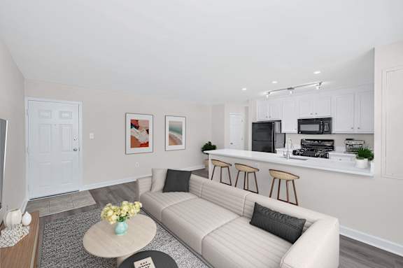 A living room with a couch, coffee table, and kitchen area in the background.