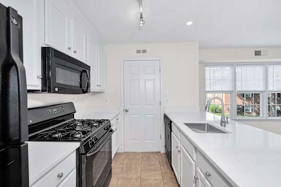 a kitchen with white cabinets and black appliances