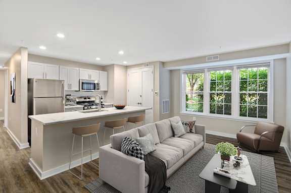 A modern living room with a kitchen area in the background.