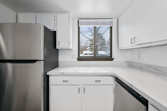 a kitchen with white cabinets and a window