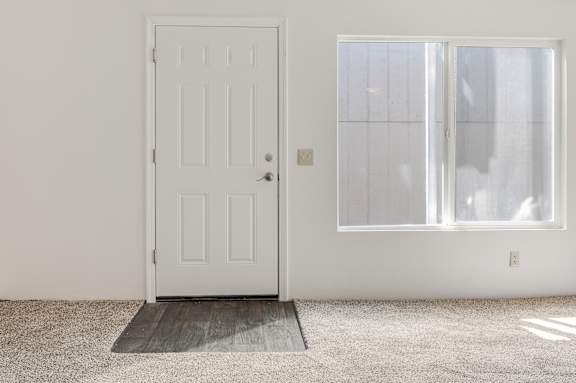 A white door is on the left and a window with blinds is on the right.