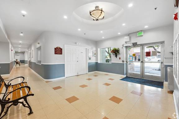 a lobby with a bench and a clock on the ceiling and a glass door